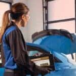 Cadillac mechanic replacing a car battery in Waukesha, WI