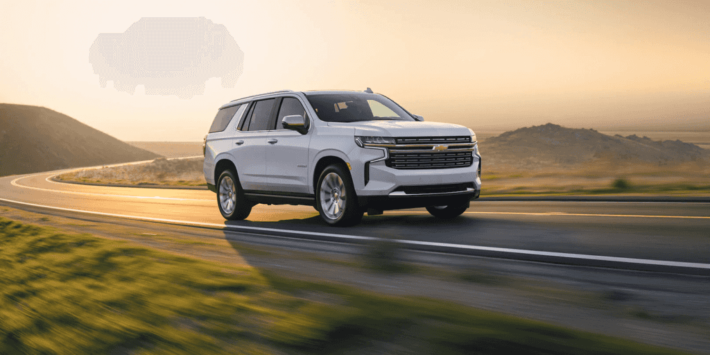 White 2022 Chevy Tahoe drives at sunset.