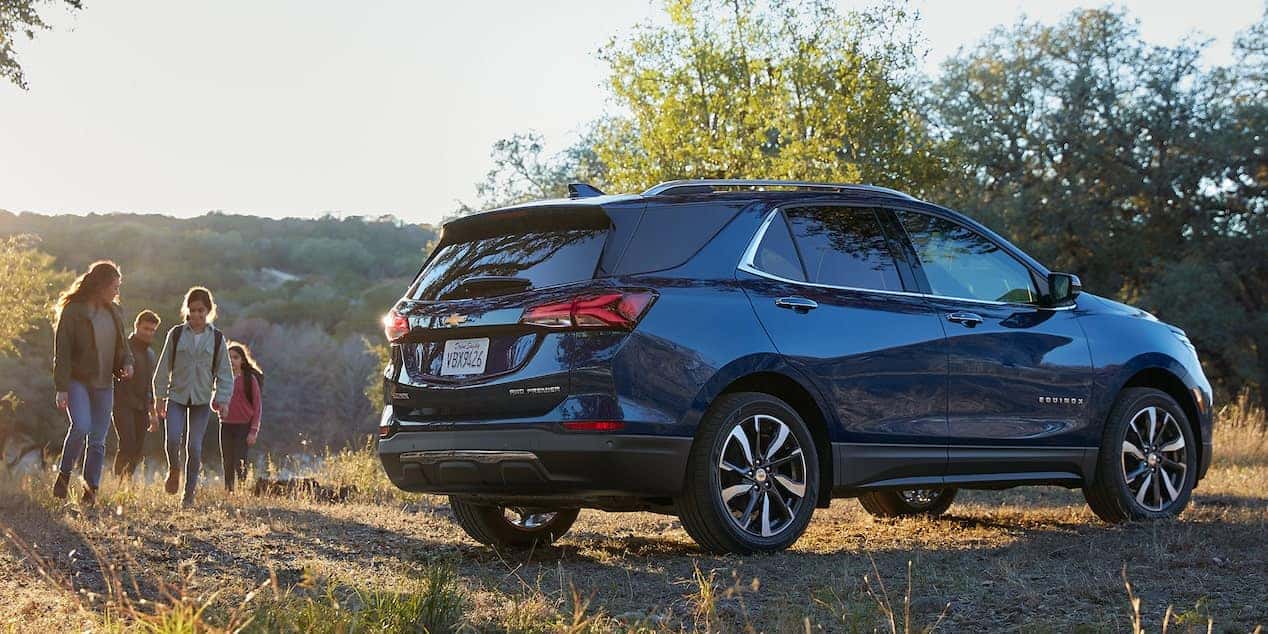 Blue 2022 Chevy Equinox parked on a road with a family of four approaching the car