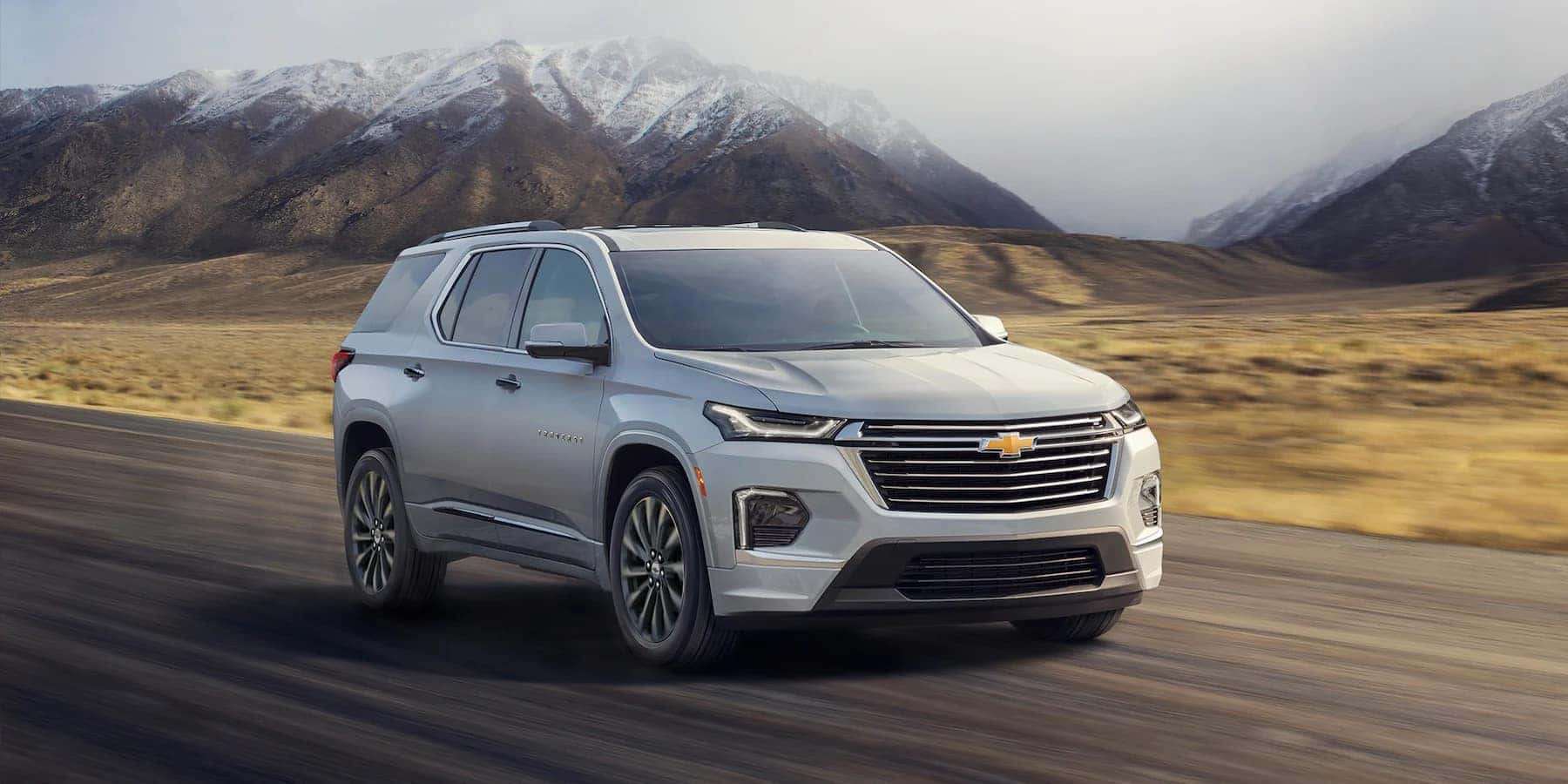 White 2023 Chevy Traverse driving with mountains in the background.