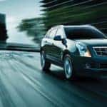 An older used car near you, a black 2012 Cadillac SRX, is shown driving on a blurred highway.