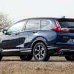 A blue 2019 Honda CR-V is facing away and parked in a field.