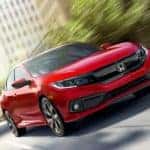 A red 2019 Honda Civic is driving on a city street near Duluth, GA.