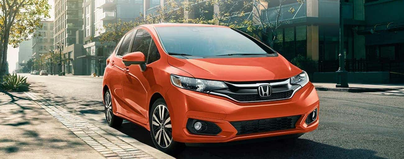 An orange 2020 Honda Fit EX-L is parked on a city street.