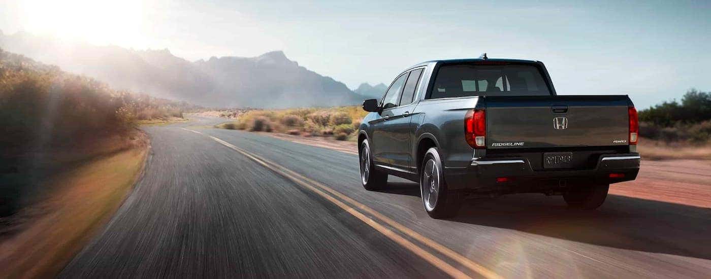 A gray 2020 Honda Ridgeline RTL-E is driving on an empty highway towards mountains.