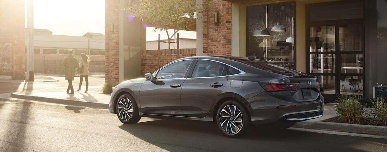 A couple is walking away from a 2021 Honda Insight on a sunny city street.