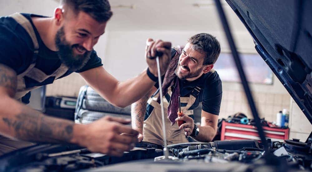 Two mechanics are working on a car at a certified Honda dealer near you.