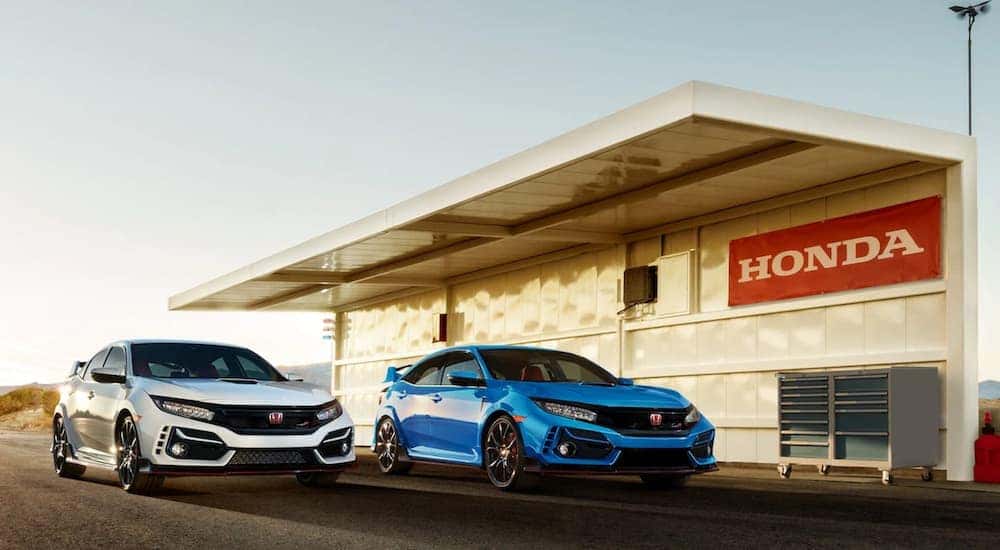 A white and a blue 2021 Honda Civic Type R have been parked next to a Honda awning and toolbox.