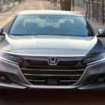 A silver 2019 Honda Accord is shown from the front driving down a city street.