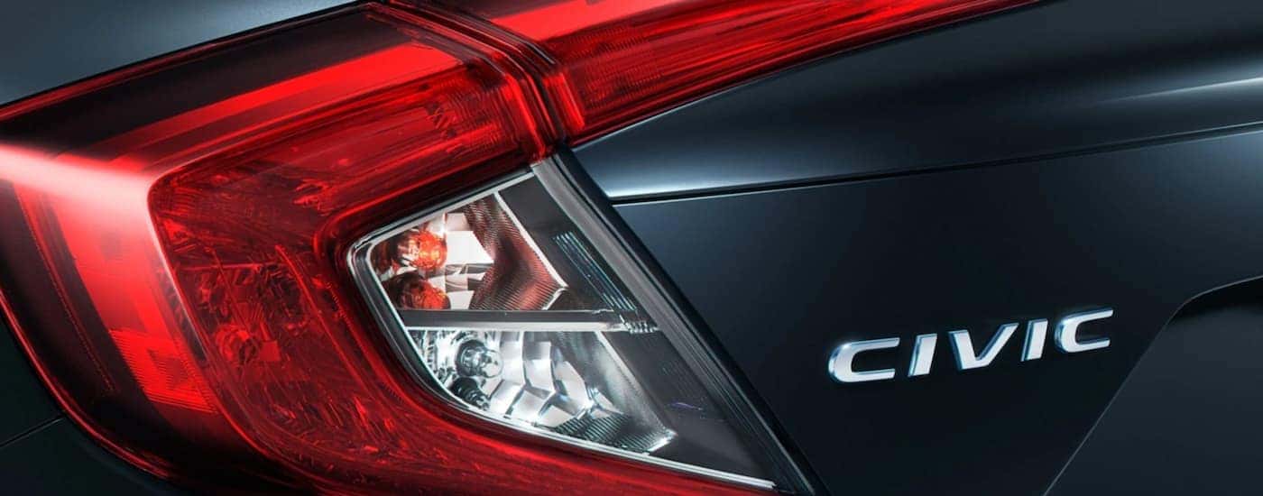 A close up shows the tail lights and Civic emblem on a dark grey 2021 Honda Civic.