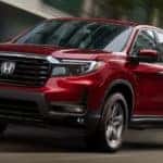 A red 2021 Honda Ridgeline RTL-E is shown driving down a street after leaving a Honda Ridgeline dealer in Atlanta.