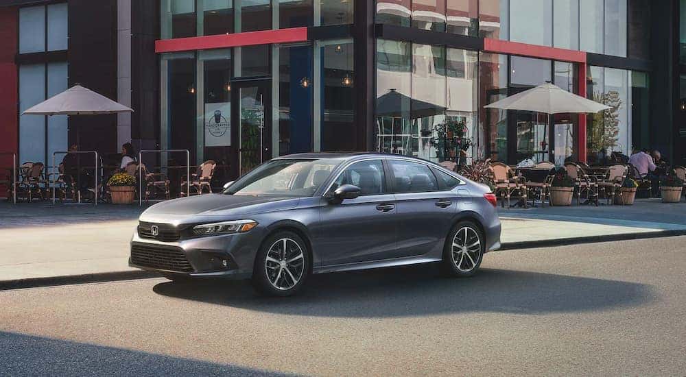 A grey 2022 Honda Civic Touring is shown parked outside a coffee shop.