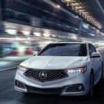 A white 2020 Acura TLX is shown driving through a city at night.