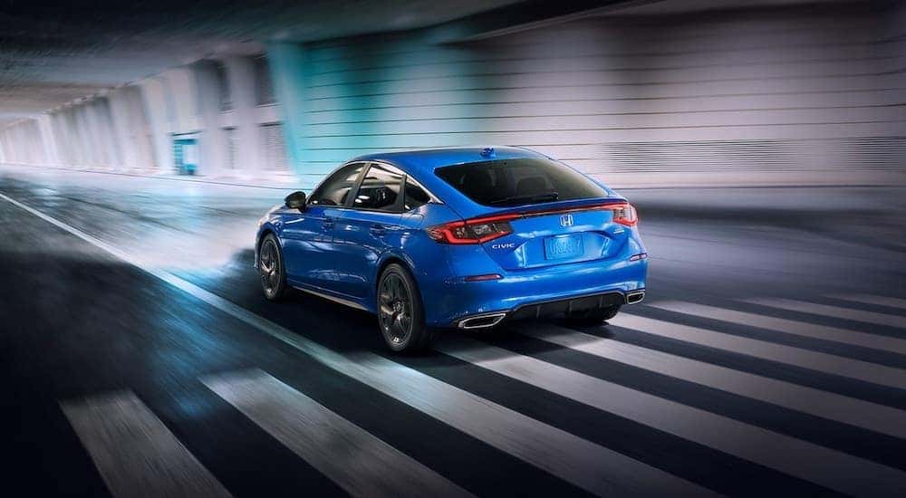 A blue 2022 Honda Civic Hatchback is shown driving through a tunnel.