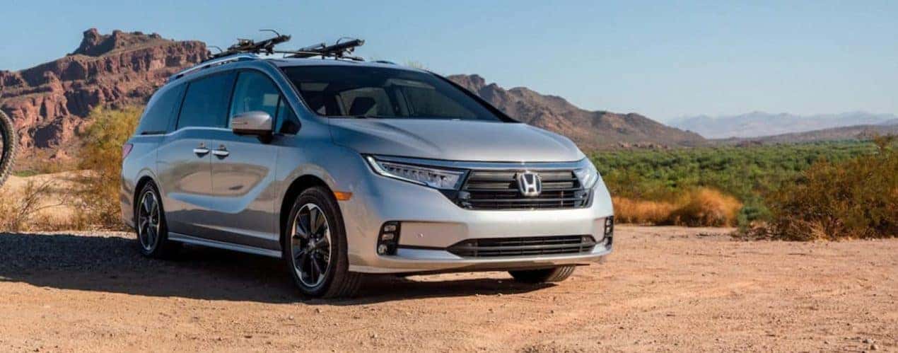 A silver 2022 Honda Odyssey Elite is shown parked in a desert during a 2022 Honda Odyssey vs 2021 Chrysler Voyager comparison.
