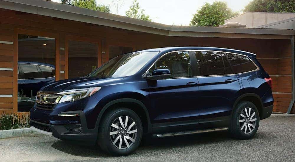 A blue 2022 Honda Pilot EX-L is shown parked in front of a modern house.