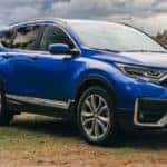 A person is taking photos next to e a blue 2021 Honda CR-V.