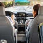 A family is shown driving a 2020 Honda Odyssey on a highway.