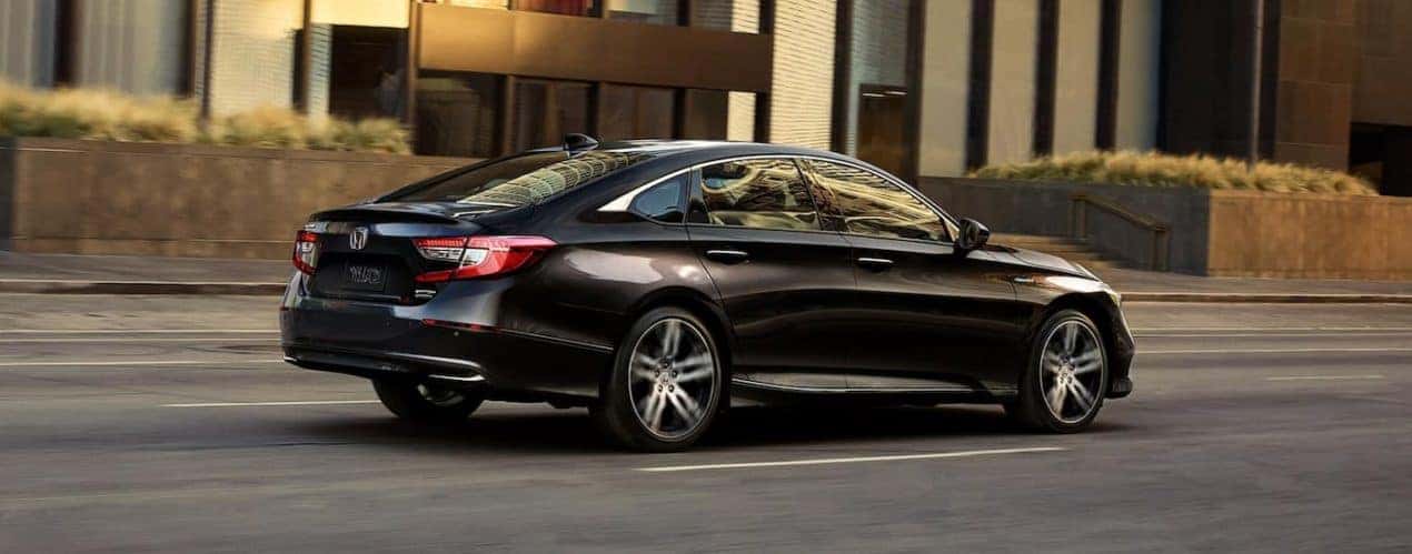 A black 2022 Honda Accord Hybrid Touring is shown from the side driving on a city street.