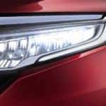 A close up shows the passenger side headlight on a red 2020 Honda Odyssey Elite.