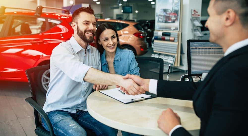 A couple is shown talking to a salesperson about selling their car after searching 'sell your car.'