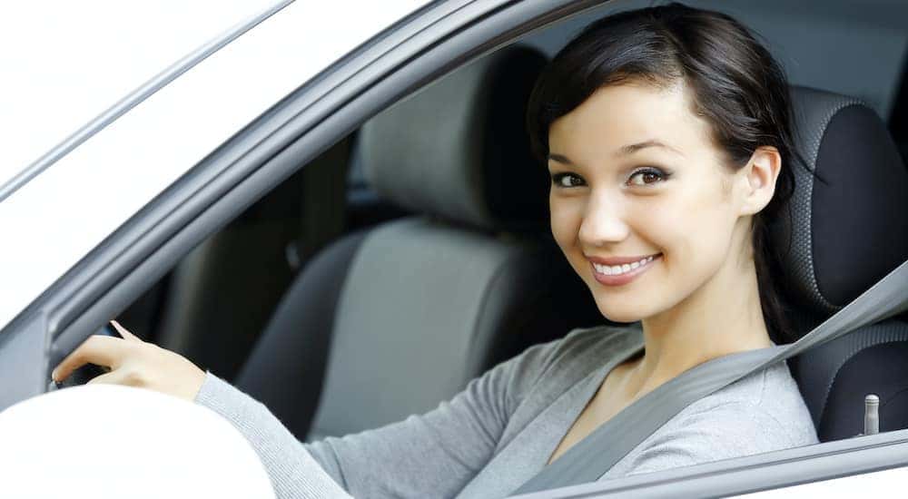 A person is shown sitting in the front seat of a car.
