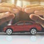 A person is shown holding their hands over a toy car.