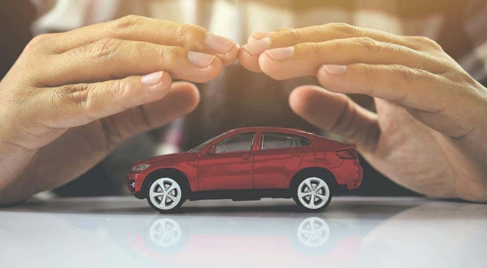 A person is shown holding their hands over a toy car.