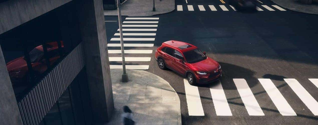 A red 2023 Honda HR-V EX-L is shown from a high angle driving through an intersection.
