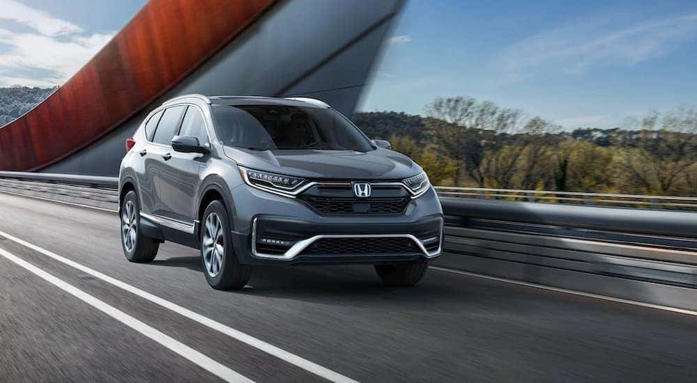 A grey 2020 Honda CR-V Hybrid is shown from the front while crossing a bridge.