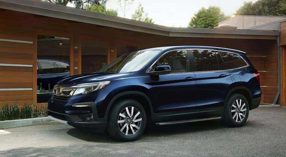 A blue 2022 Honda Pilot is shown parked in front of a garage.