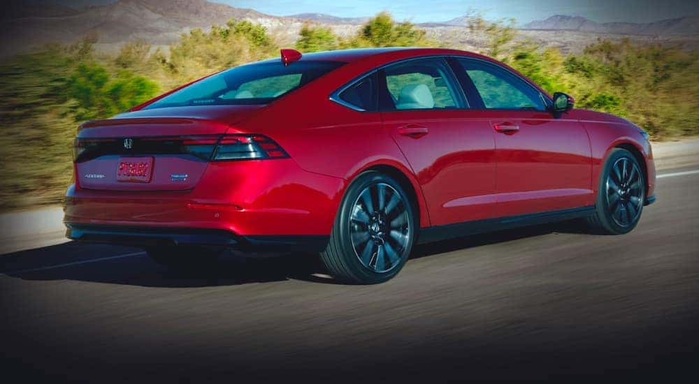 A red 2023 Honda Accord is shown from the side driving on a road.