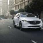 White Mazda CX-5 driving dow the raod.