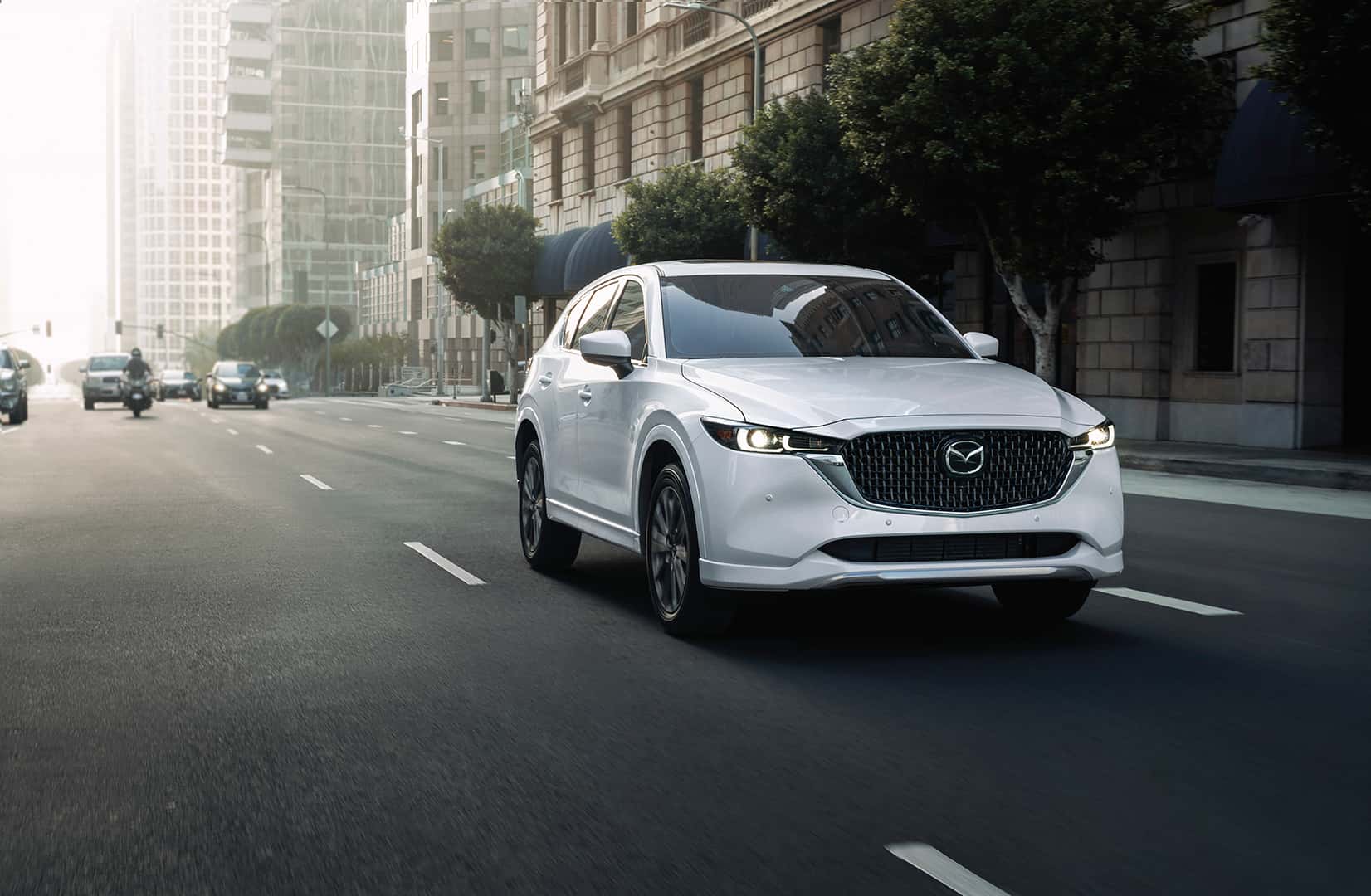 White Mazda CX-5 driving dow the raod.