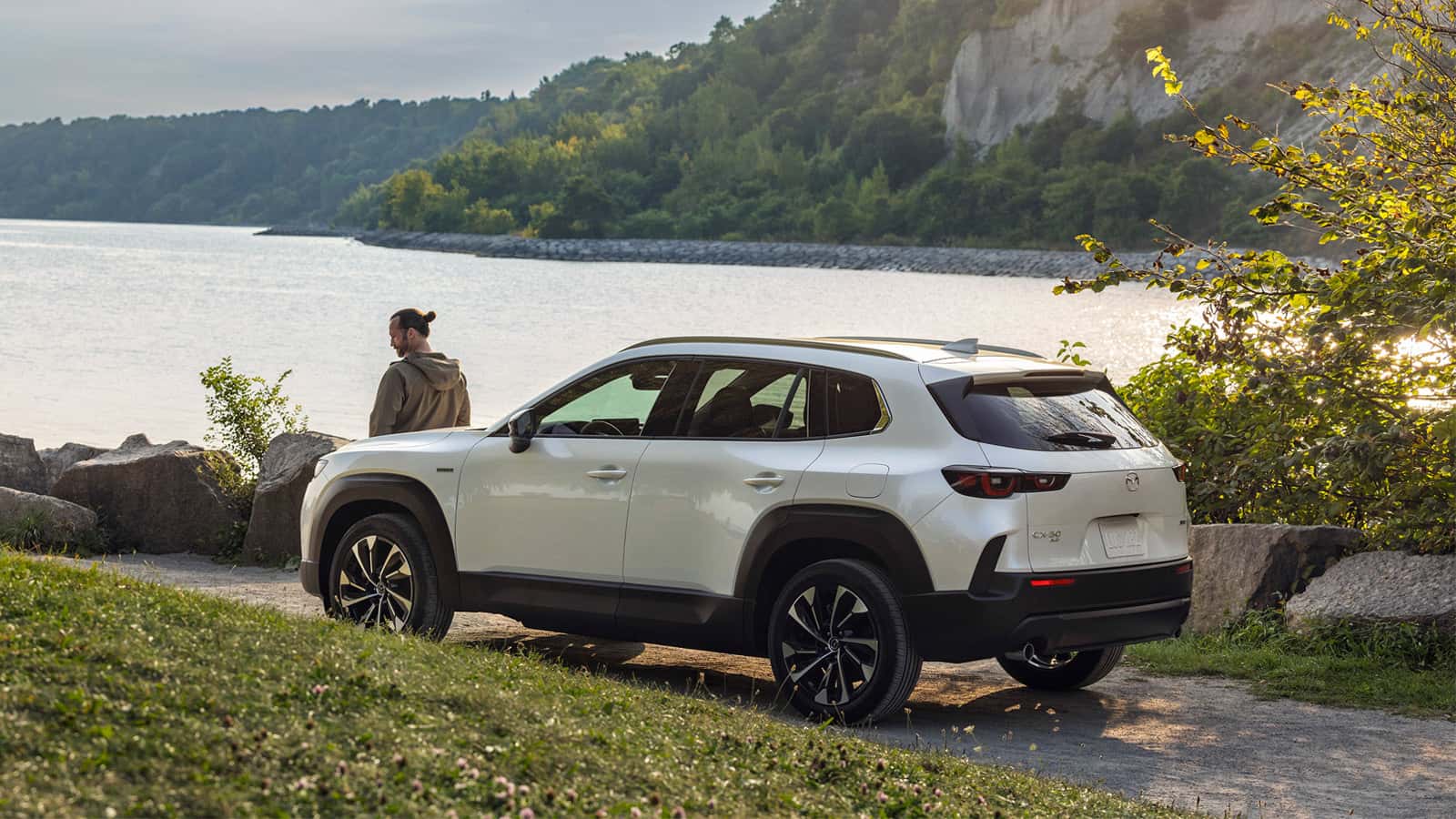 MAZDA CX-50 Hybrid overlooking a lake with a person on the hood.