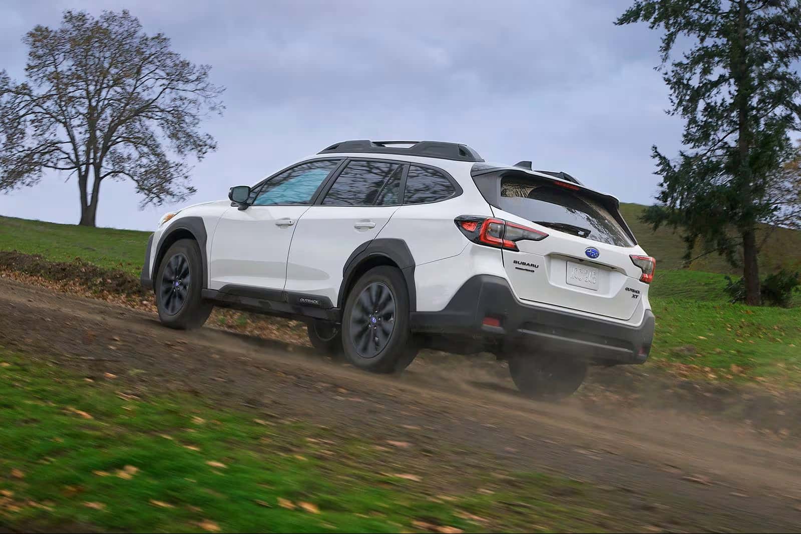 A white 2025 Subaru Outback driving up a dirt road.