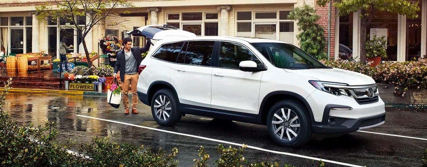 Man loading flowers into the back of a white 2020 Honda Pilot EX-L in front of a shop