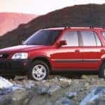 One of the original Honda SUVs, a red 1997 Honda CR-V, is parked on a rocky mountain.