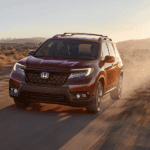 A red 2020 Honda Passport is driving in a desert.