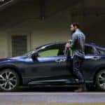 A blue 2021 Honda Civic is shown in profile with a man opening the driver door.