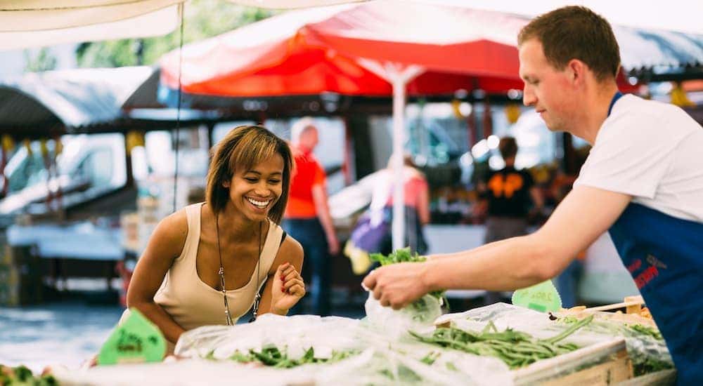 Woman smiling as a vendor is packing up the vegetables she bought at the farmer's market