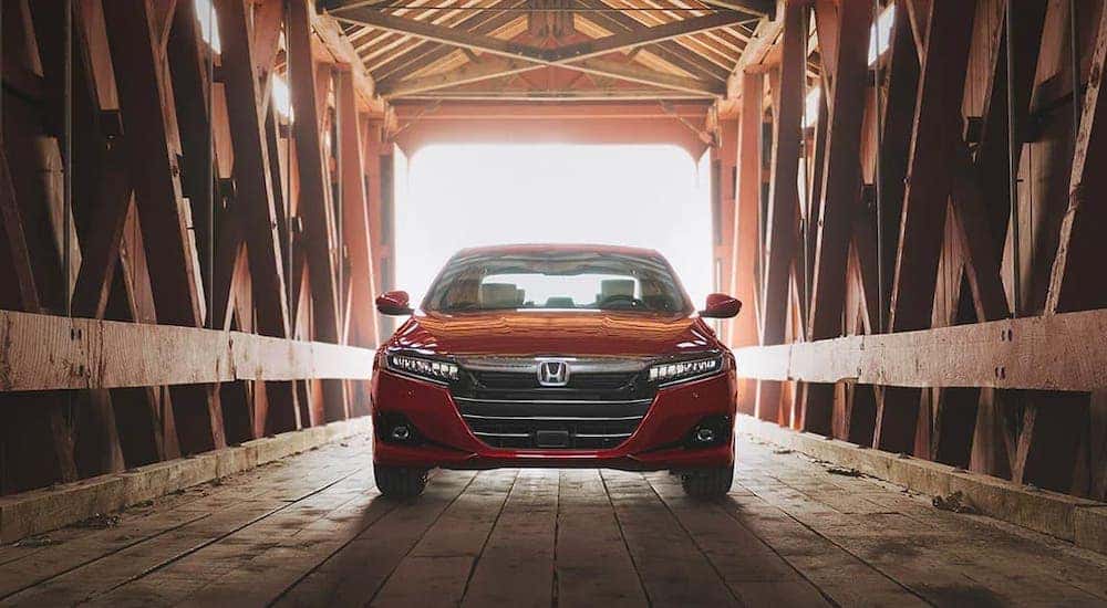 A red 2021 Honda Accord Touring 2.0T is shown from the front while parked in a wooden covered bridge.