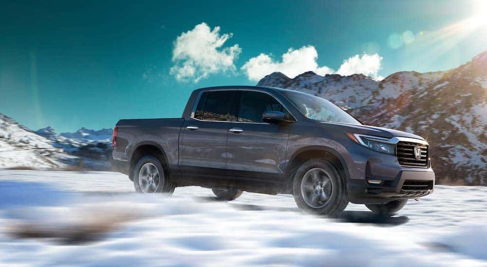 Side view of a grey 2021 Honda Ridgeline RTL-E driving through a snowy field