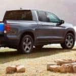A grey 2021 Honda Ridgeline RTL-E is shown being unloaded at a camp site near a lake.
