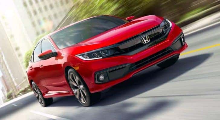 Front view of a red 2021 Honda Civic sedan driving down a city street