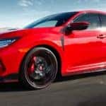 A red 2021 Honda Civic Type R hatchback is shown from the side speeding down the blacktop after leaving one of the Honda dealers in Atlanta.