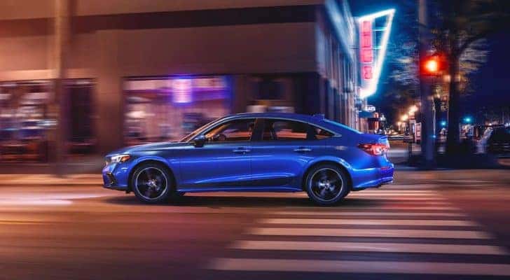 A blue 2022 Honda Civic Touring is shown form the side driving through a city after leaving a Fayette County Honda dealership.