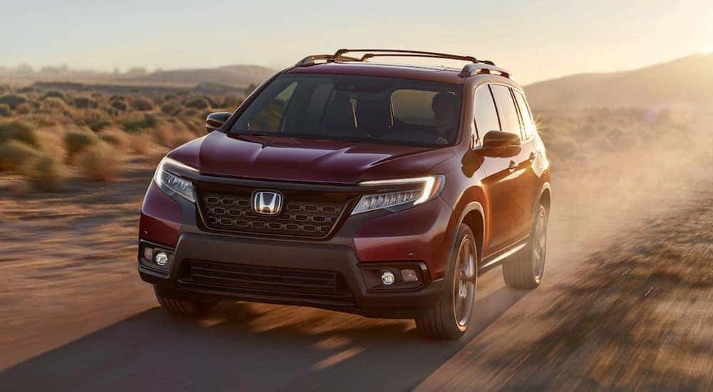 Front view of a red 2021 Honda Passport AWD Elite off-roading through the desert