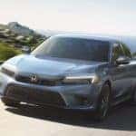 A grey 2022 Honda Civic Sport is shown from the front driving past a body of water.