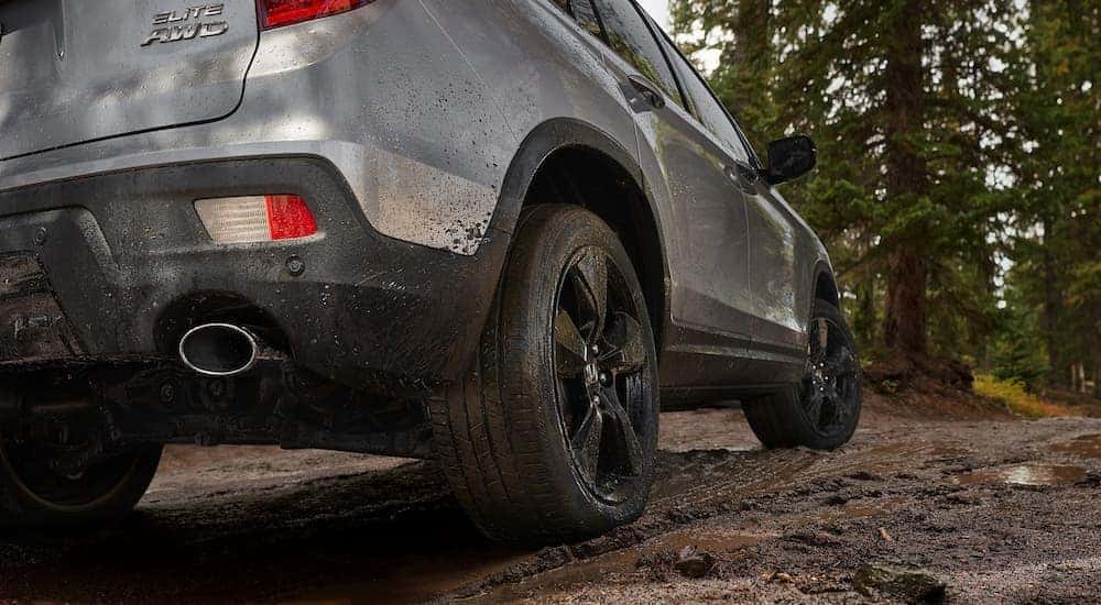 Back view of the lower half of a 2022 Honda Passport Elite driving through a mud trail